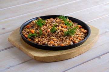 Buckwheat with fried mushrooms, carrot and onion in cast iron pan