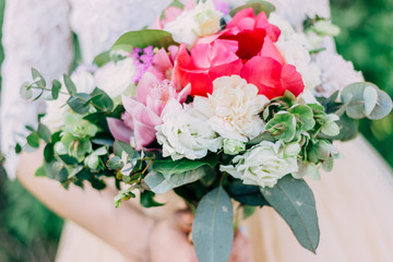 The bride holds a beautiful wedding bouquet of pink and white flowers in her hands