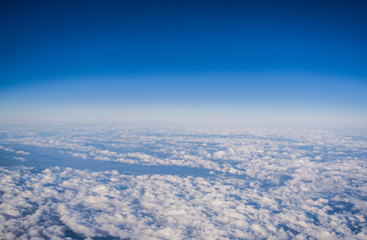 View from a plane window on clouds and blue clear sky and the earth from height. Beautiful view from air of mountains. 