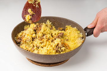 Frying pan full of yellow rice minced meat on white