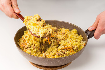 Frying pan full of yellow rice minced meat on white