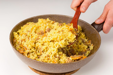 Frying pan full of yellow rice minced meat on white