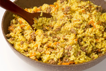 Frying pan full of yellow rice minced meat and wooden shovel