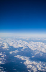 Obraz na płótnie Canvas View from a plane window on clouds and blue clear sky and the earth from height. Beautiful view from air of mountains. 