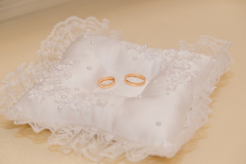Wedding rings on a white pad and a wooden light table.