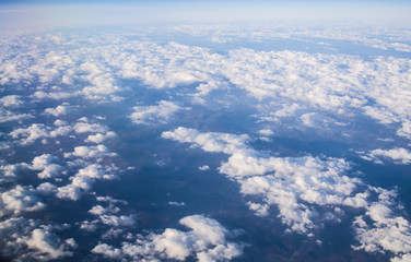 View from a plane window on clouds and blue clear sky and the earth from height. Beautiful view from air of mountains. 