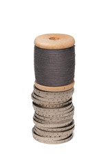 Rows of coins isolated on white background next to multicolored thread on wooden spool