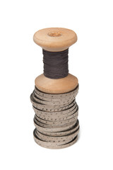 Rows of coins isolated on white background next to multicolored thread on wooden spool