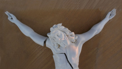 Fototapeta na wymiar A broken ceramic representation of the crucified Christ with outstretched nailed hands