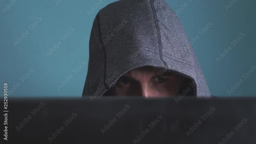 Wall mural man hacker in the hood hacking network concept. unknown hacker criminal breaks into computer protect