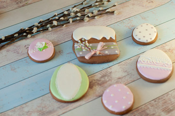 easter cookies in shape of holiday bread, eggs laying on light wooden background near pussy-willow branches