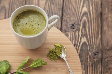 cup of Matcha tea on a round wooden tray