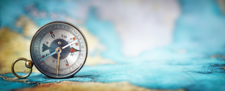 Magnetic old compass on world map.Travel, geography, navigation, tourism and exploration concept wide background. Macro photo. Very shallow focus.