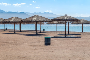 Straw umbrellas on the beach at sunny day.