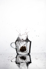 splash of water from a mug on a white background. Reflection and small drops on a horizontal surface. Vertical view.