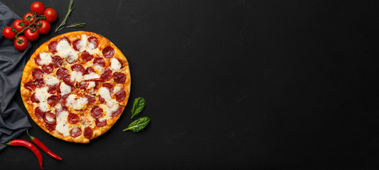 Pepperoni pizza on black background, top view