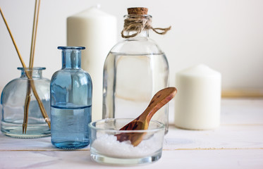 Natural organic cosmetics in glass bottles, near candles, sea salt and incense sticks. Spa skin care, home spa. Bottles with lotion on wooden background.