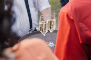 Woman holds two glasses of champagne on a tray.