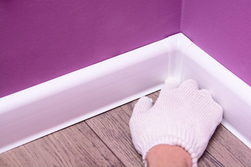 technology of installation of a white floor plinth. home improvement concept