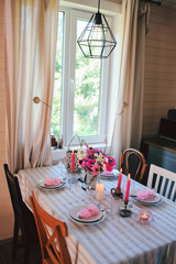 summer country house kitchen interior in rustic natural style. Table decorated for family or romantic dinner.
