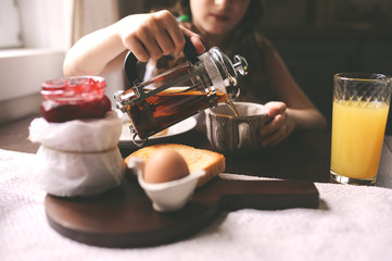 happy kid girl having breakfast at home, eating toast with jam and eggs on farmhouse kitchen