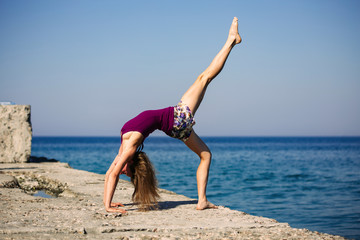 Fototapeta na wymiar pretty girl standing on one foot yoga pose on the beach background