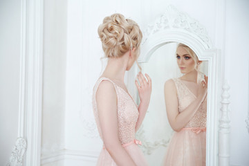 Gentle portrait of a beautiful bride with an elegant wedding hairstyle in front of a mirror.