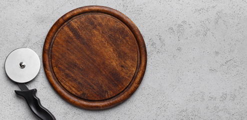 Wooden cutting board and pizza cutter, top view