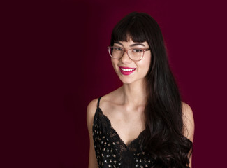 Portrait of a Beautiful Young Smiling Girl Wearing Glasses Against a Purple Backdrop