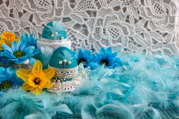 Wielkanocna kompozycja z niebieskiemi pisankami ozdobionymi koronką, żółtymi kwiatami, błękitnymi piórami © Monika