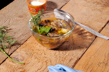 Mushroom soup with dill, on wooden background in a glass bowl