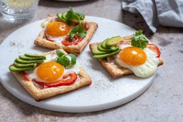 Fototapeta na wymiar Baked puff pastry with fried egg, pepper and avocado