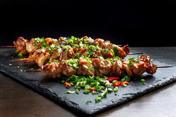 Grilled meat skewers, shish kebab on black slate.