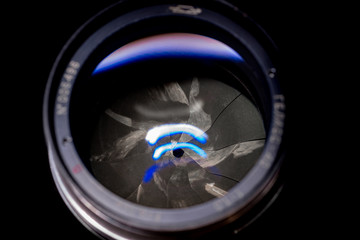 Lens aperture low light photo closeup. Blue traces on glass. Aperture blades is dirty and partially...