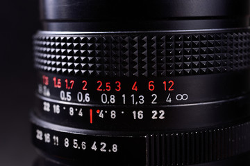 Vintage lens scales symbols closeup. Stock photo with blurred gray background. Aperture symbols and focusing distance signs on lens.