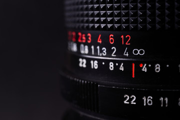 Vintage lens scales symbols closeup. Stock photo with blurred gray background. Aperture symbols and focusing distance signs on lens.
