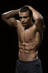 Fototapeta premium Perfect body. Vertical shot of an African man with toned body posing shirtless in studio