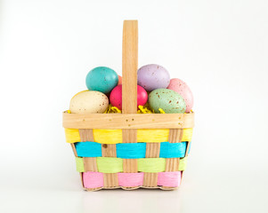 brown wicker Easter basket filled with colorful speckled Easter eggs isolated on white