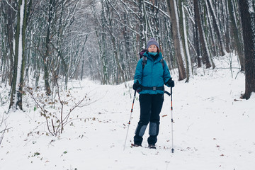 Young girl with backpack hikes through the winter forest