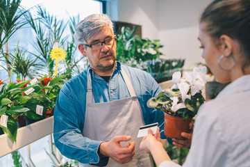 woman buying flowers with credit card in flower shop