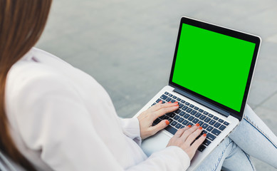 Millennial woman typing on laptop with green screen