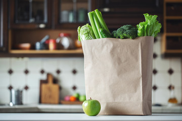 Fresh green vegetables and fruits in a paper bag.