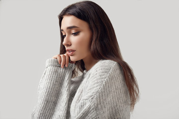 Beautiful brunette woman in sweater posing in studio