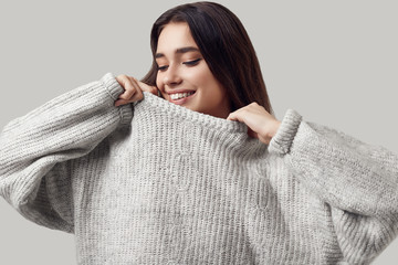 Beautiful brunette woman in sweater posing in studio