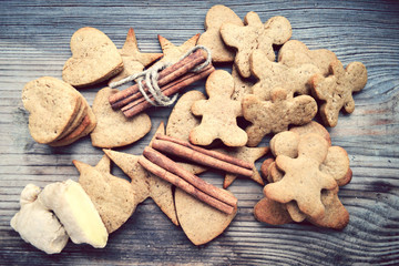 Gingerbread cookies in shapes of heart, star and man with cinnamon stick and ginger root on wooden table