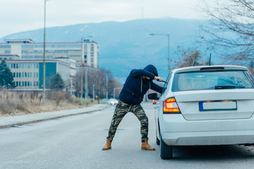 Gangster with a gun trying to rob a guy which is sitting in his car.