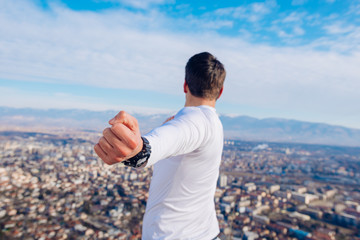 A young strong fit masculine man working out in the morning while looking at the city.