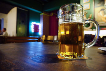 Big pint of beer on wooden table close up view