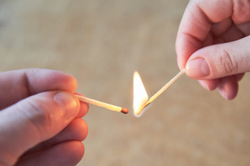 The hand of a man and a woman hold burning matches