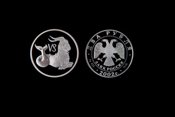 Silver coin of the Bank of Russia with the sign of the zodiac Capricorn on a black isolated background. The coin says: "Two rubles. Bank of Russia".